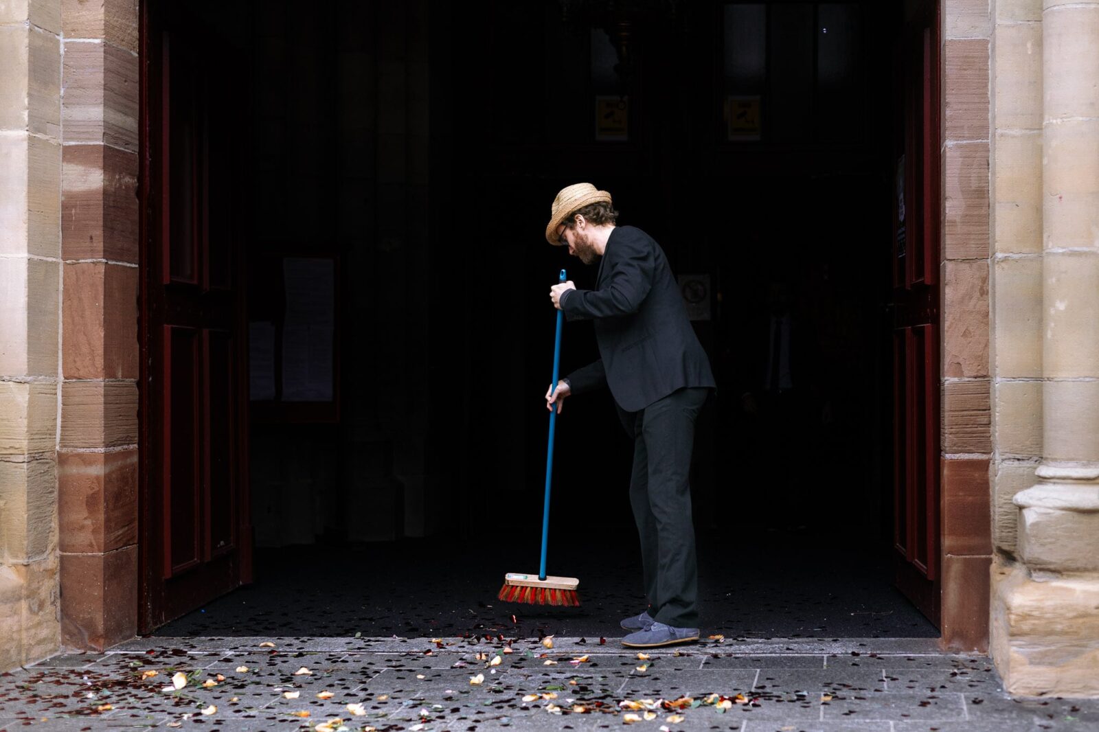 Un invité qui nettoie devant l'église lors d'un mariage à Mulhouse par Clement Renaut, photographe de mariage en Alsace