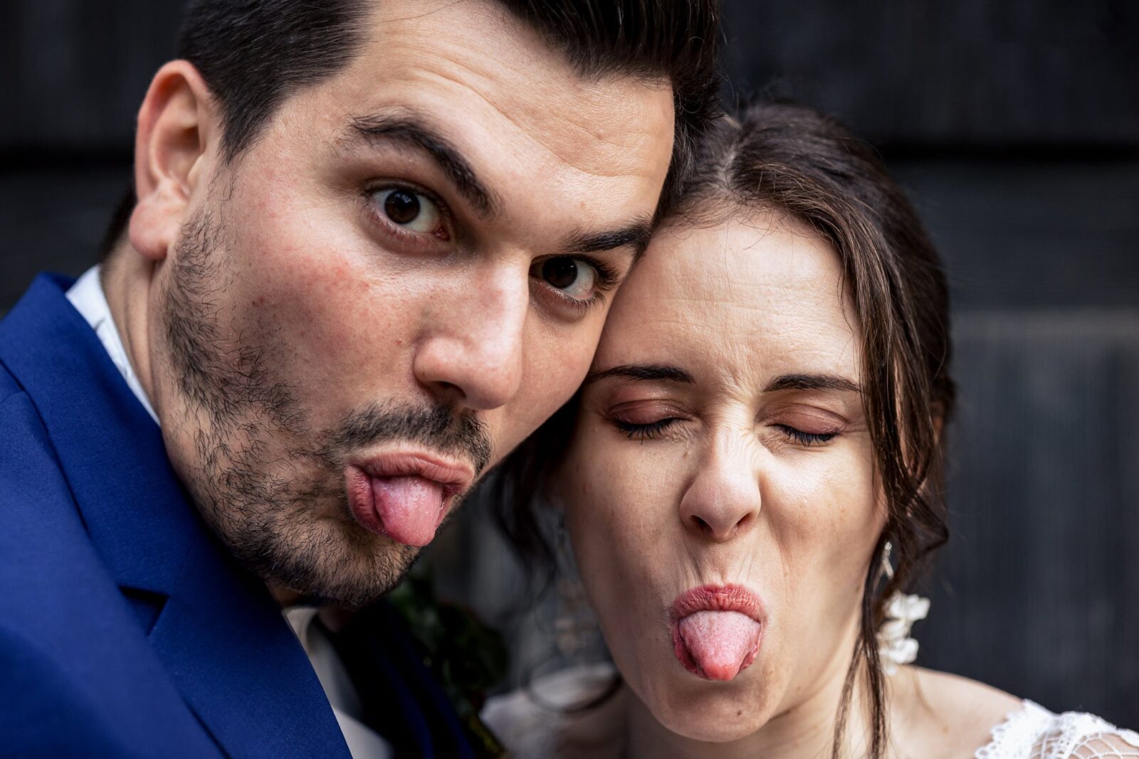 Les mariés qui tirent la langue pendant une séance photo à lécomusee d'alsace par Clement Renaut, photographe de mariage en Alsace